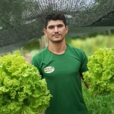 man with mustache in green short holds lettuce in both hands