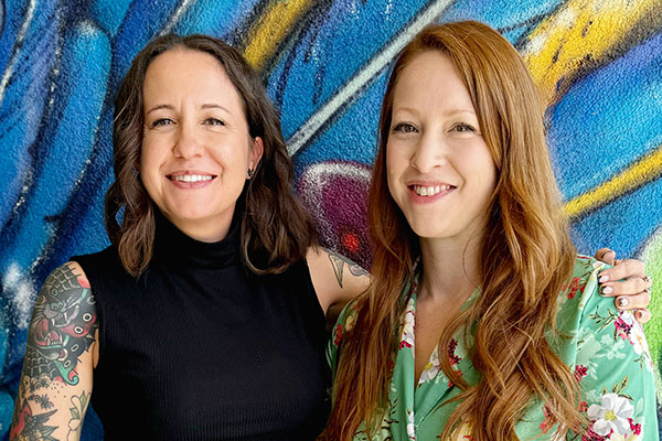 two women smiling in front of colorful background