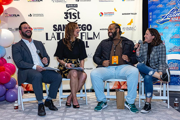 two men and two women laugh on a stage