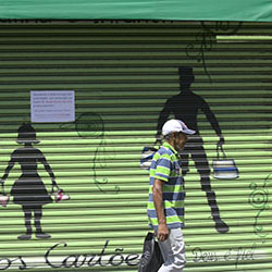 man walking in favela, grafitti about covid in background